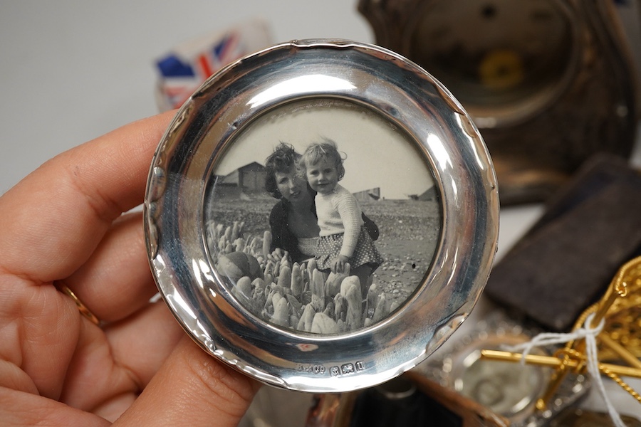 A collection of sundry silver items to include a silver mounted timepiece, hexagonal pill box and photo frames, one housing a hand painted porcelain portrait plaque, largest 12cm high